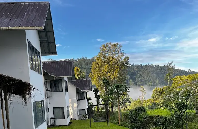 Exterior view of white villa cottage building surrounded by green gardens at Mannoor Farmstay Munna