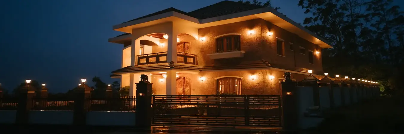 Scenic aerial drone view of Eve Munnar Luxury Resort surrounded by a tranquil lake and lush green mountains