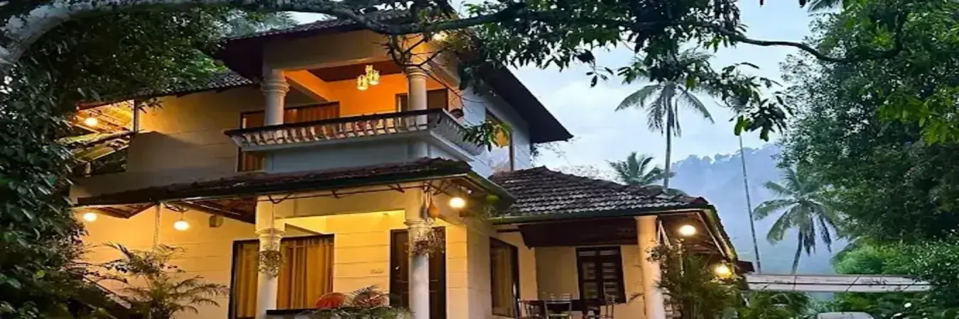 Night view of illuminated Thoppil Homestay building nestled in the hills of Munnar