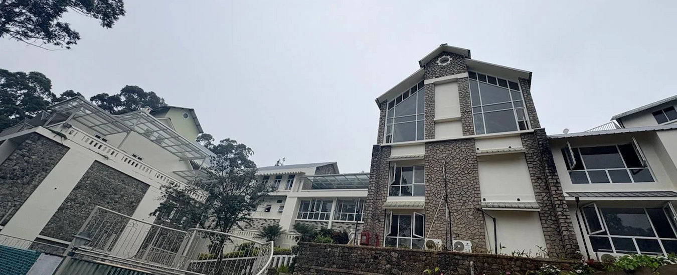 Colonial style stone bungalow exterior of 1924 Clock House Resort Munnar