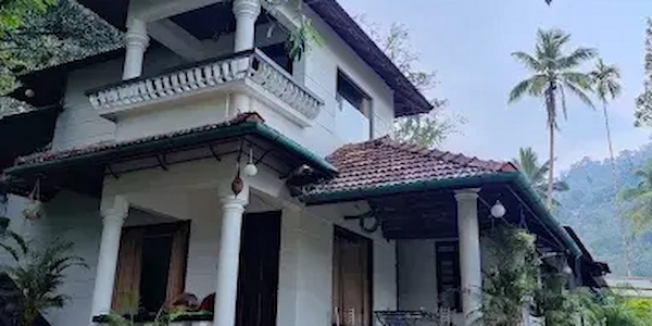 Exterior view of Thoppil Homestay building surrounded by greenery in Munnar