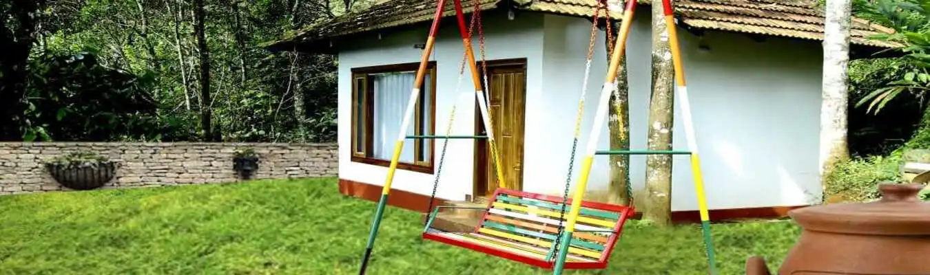 Exterior front view of Kurinjiyil FarmStay property surrounded by lush plantation greenery in Munnar
