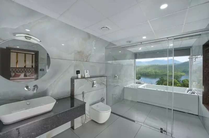 Modern luxury bathroom featuring a sleek freestanding bathtub and a scenic window view at Eve Munnar Luxury Resort