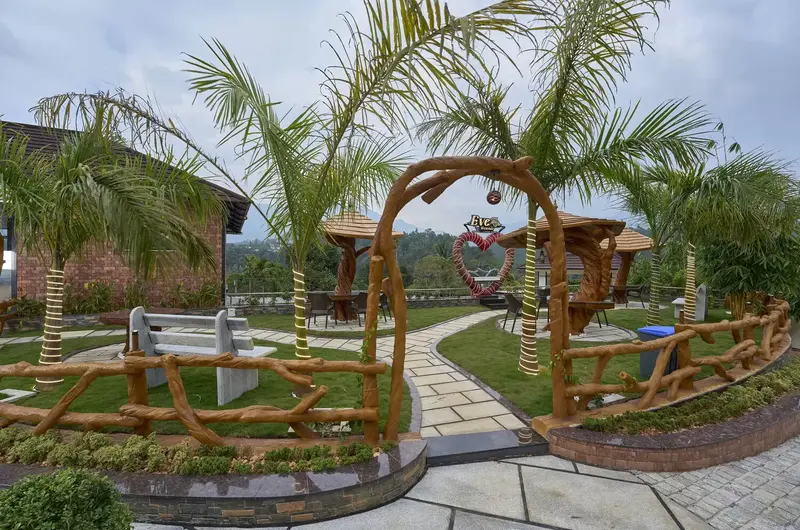 Manicured garden pathway with decorative archways and palm trees at Eve Munnar Luxury Resort