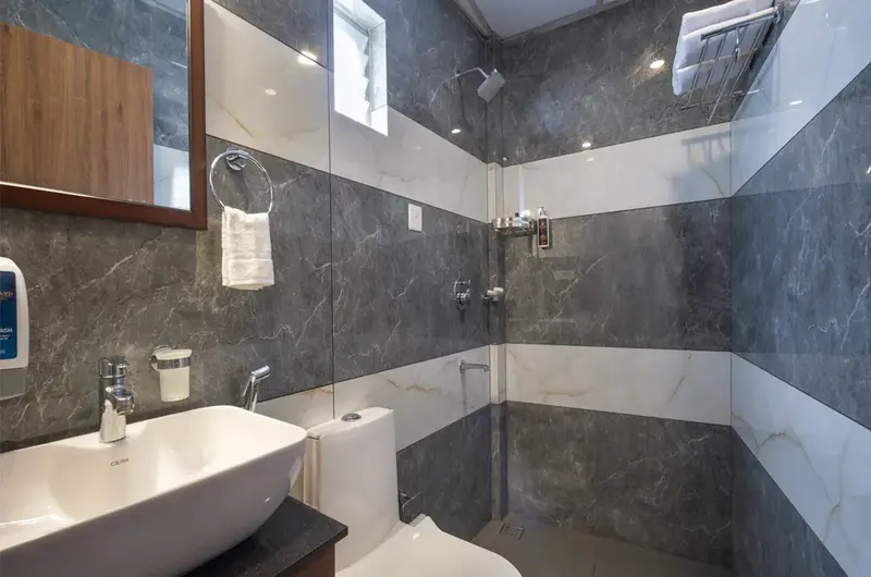 Modern luxury bathroom with grey marble tiling and premium fixtures at Boulevard Hotel Munnar