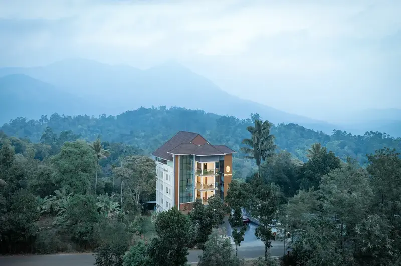 Scenic drone view of Boulevard Hotel Munnar nestled in lush green hills and misty mountains
