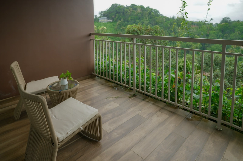 Private room balcony with glass railing overlooking green hill slopes at Mountree Munnar