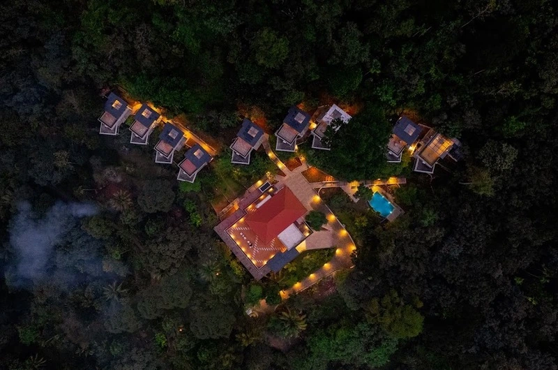Nighttime aerial view of lit cottages at Maram Resort in Mamalakandam