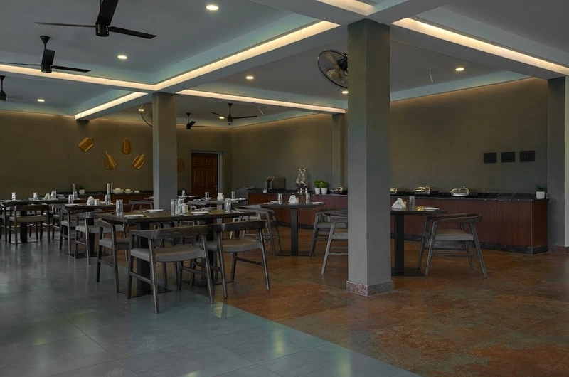 Spacious indoor dining restaurant hall with modern ceiling lighting at Maram Resort Mamalakandam