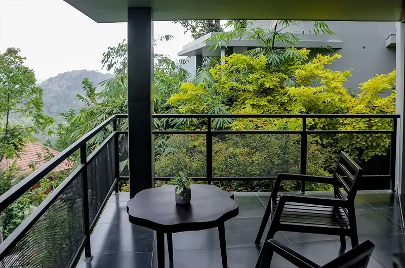 Private cottage balcony with seating area overlooking nature at Maram Resort Mamalakandam