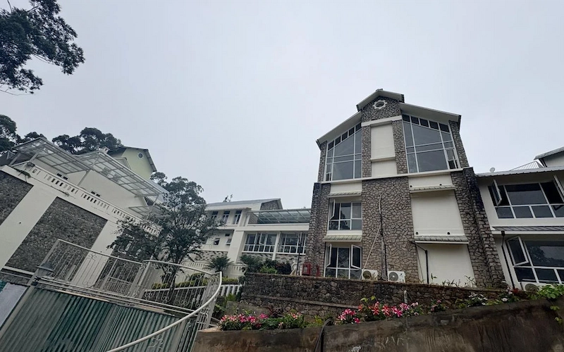 Colonial style stone bungalow facade of 1924 Clock House Resort Munnar