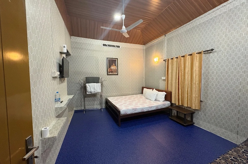 Spacious farm stay guest room with comfortable bed and wooden ceiling in Munnar
