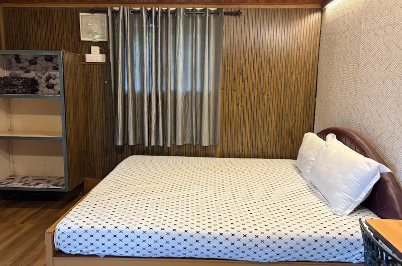 Warmly lit bedroom interior with double bed at Pepper County Farm Stay Munnar