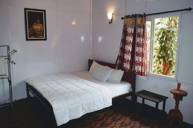Elegantly furnished guest bedroom featuring white bedding and curtained window in Munnar