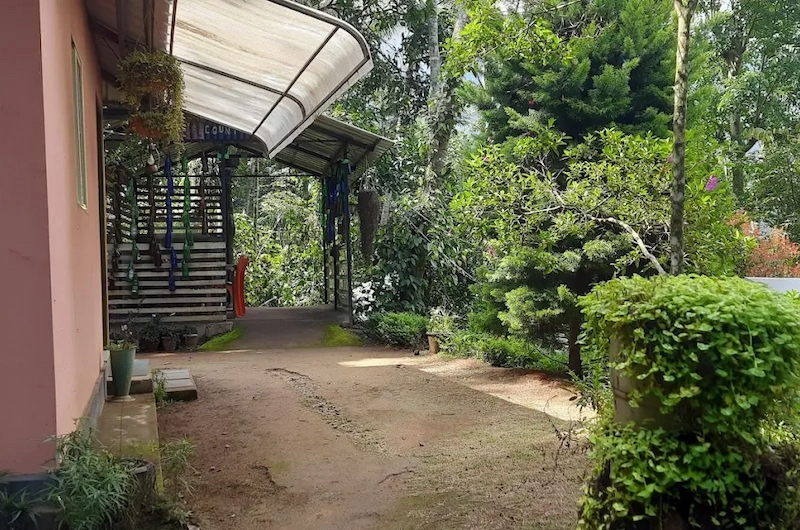 Paved garden walkway and covered outdoor sitting area surrounded by spice plantations in Munnar