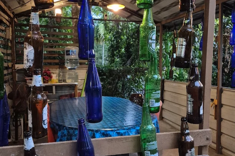 Outdoor dining and sitting area nestled under lush green foliage at Pepper County Farm Stay Munnar