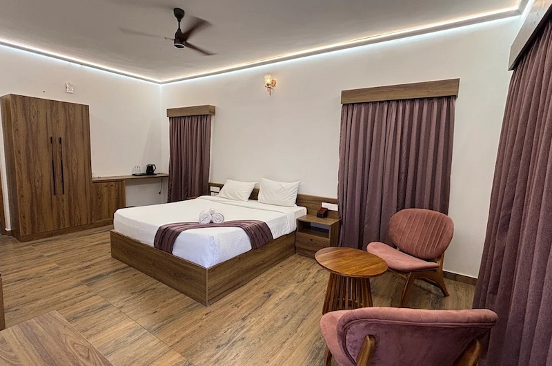 Modern guest room suite with comfortable double bed and wooden furniture at The Hamlet Farmstead Munnar