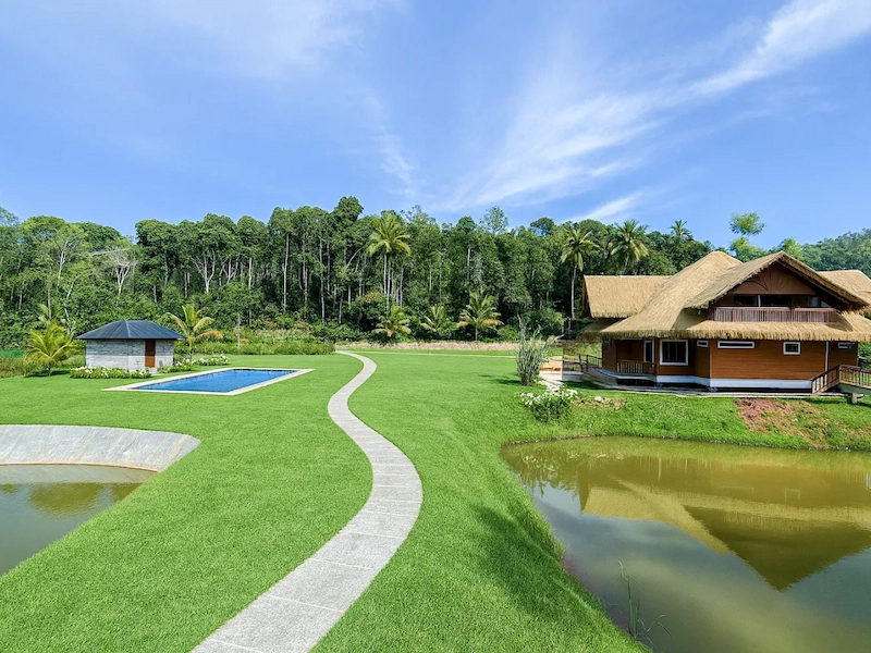 Landscaping gardens with paved walking paths and lush green hills at The Hamlet Farmstead Munnar
