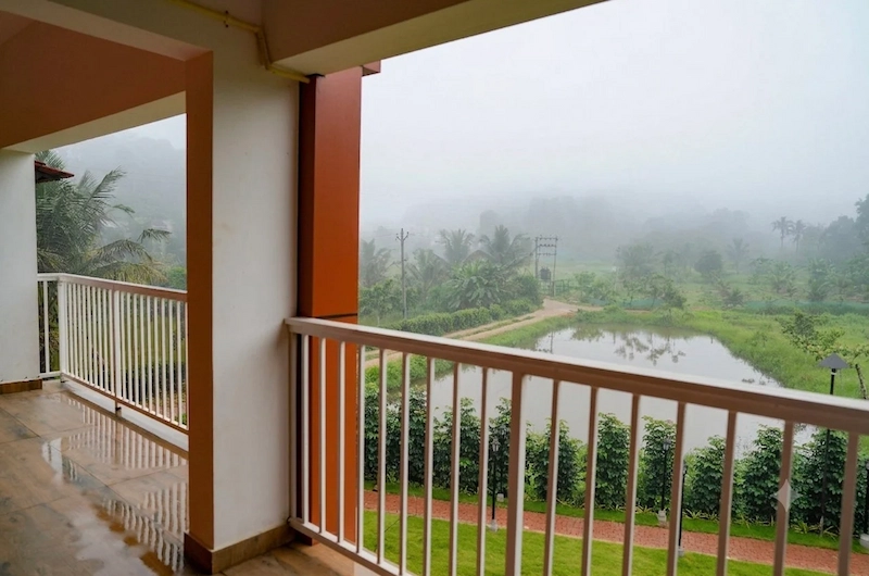 Spacious resort room balcony with modern seating overlooking lush green hills at The Hamlet Farmstead Munnar