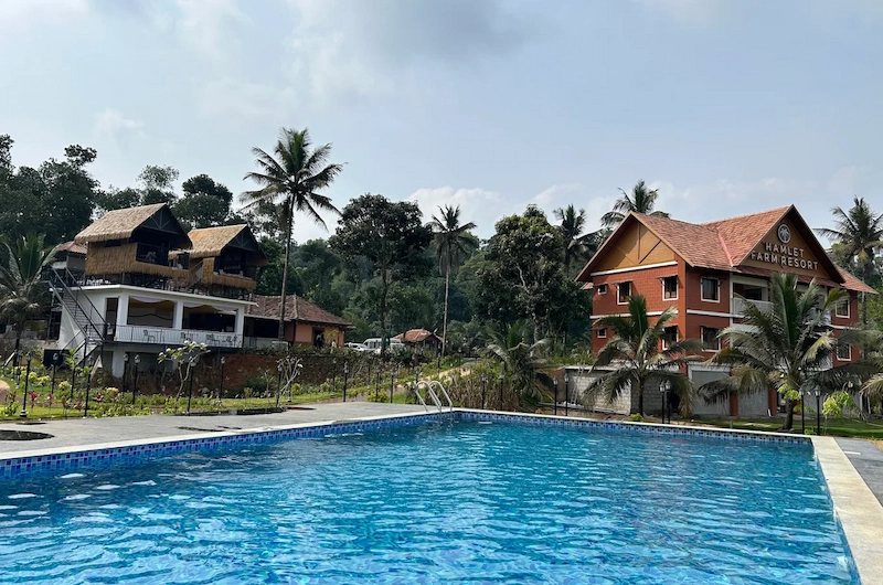 Resort cottage and swimming pool set against scenic green hill landscape at The Hamlet Farmstead Munnar