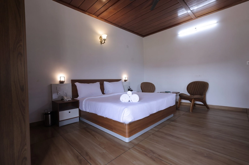 Elegantly furnished resort bedroom with white linens and warm lighting at The Hamlet Farmstead Resort Munnar