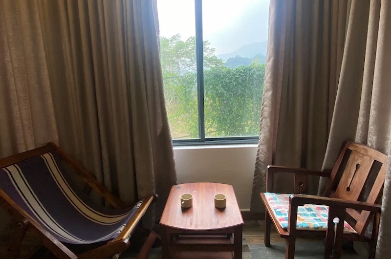 Spacious guest bedroom with plush bedding and seating area at Mannoor Farmstay Munnar