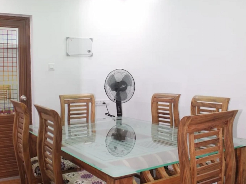 Cozy living room area with wooden dining table and chairs at 4 Acre Woods Farm Stay Munnar