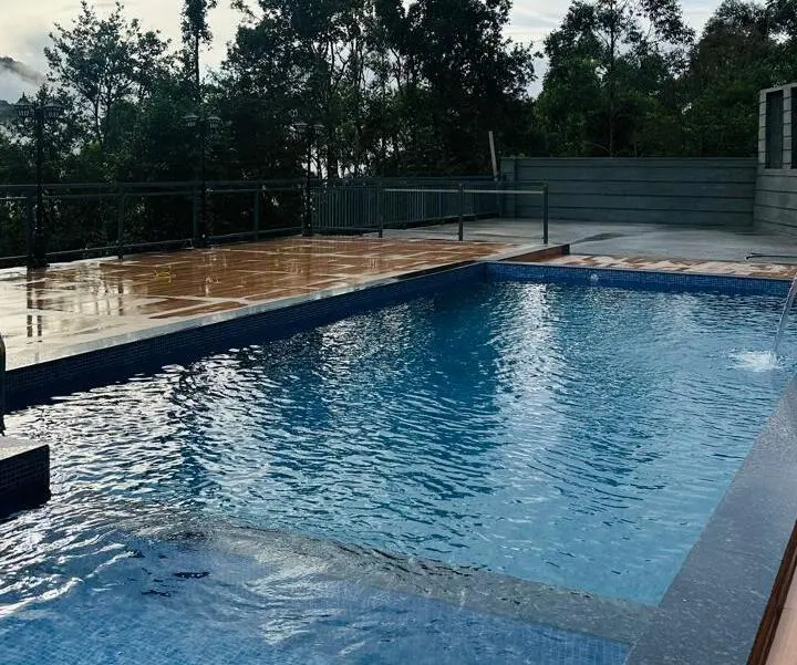Scenic outdoor swimming pool at Tea Tree Resort Munnar overlooking hill station trees