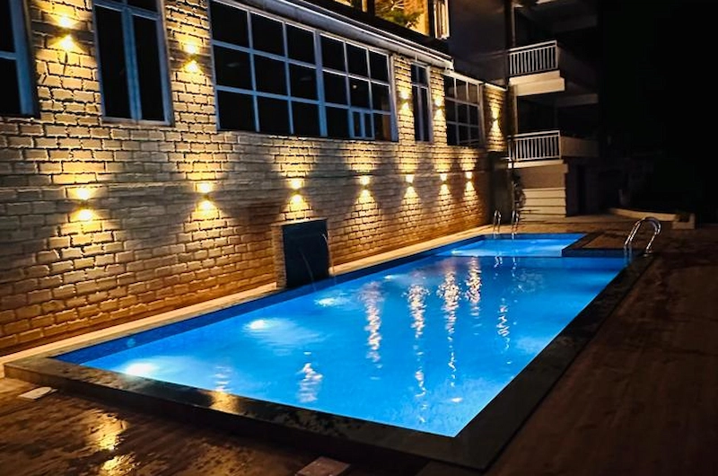 Illuminated outdoor swimming pool at Tea Tree Resort in Munnar during night
