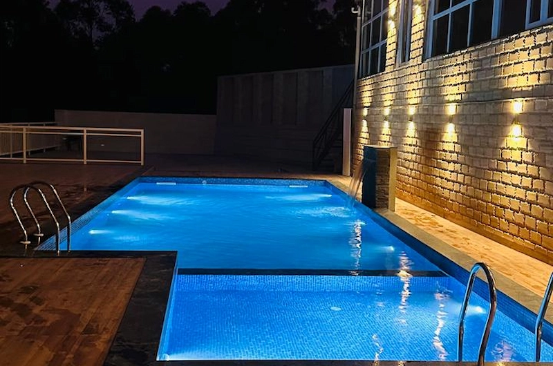 Night view of the swimming pool deck at Tea Tree Resort Munnar lit with warm lights