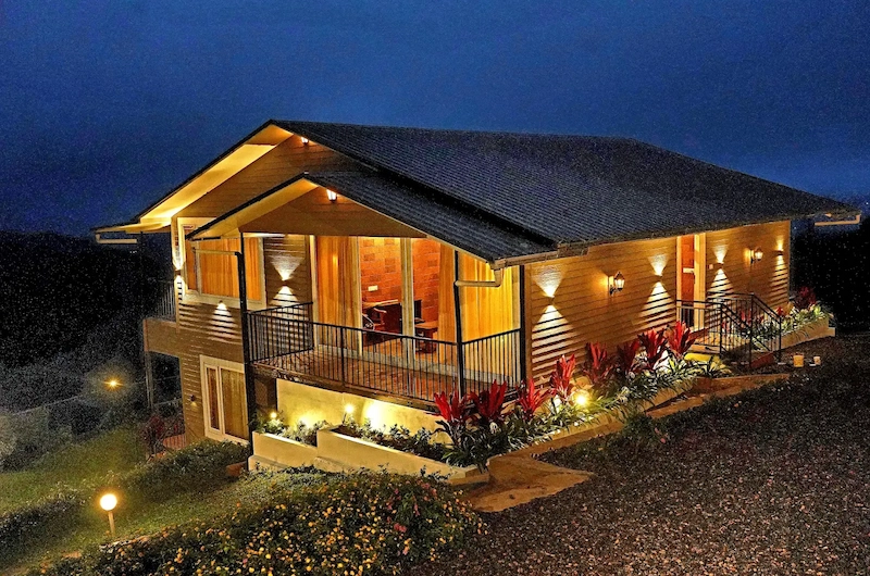 Night view of warm lit wooden eco lodge nestled in nature at Wild Lilly