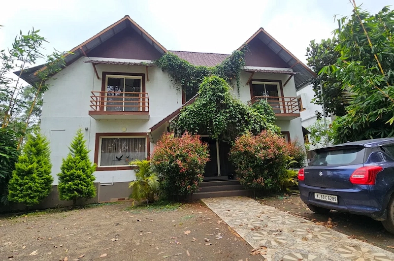Traditional hillside cottages and guest parking area at Flamingo Resort Munnar