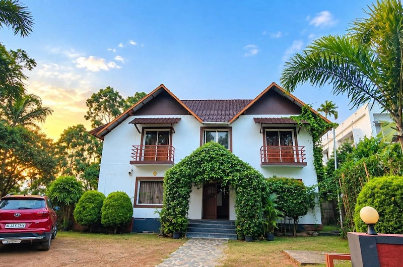Exterior view of Flamingo Resort with green lawn and tiled roof cottages in Munnar