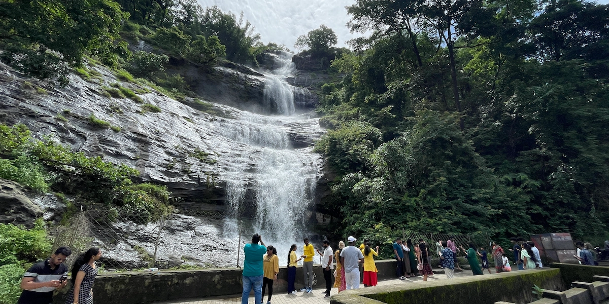 Scenic waterfall stream cascading over rocky steps in lush tea garden landscape Munnar