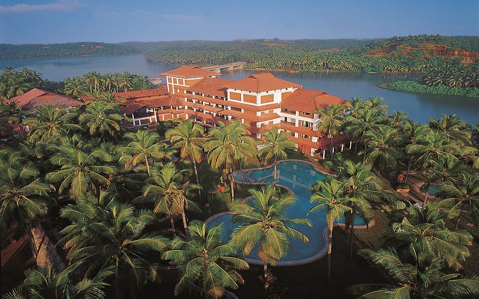 Aerial view of luxury tropical resort surrounded by lush palm trees and swimming pool in Kozhikode