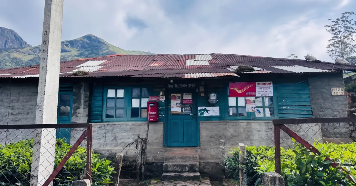 Historic stone building of Suryanelli Sub Post Office surrounded by green tea plantations in Munnar Kerala